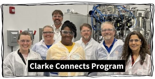 Group of seven people wearing white smocks in a labratory