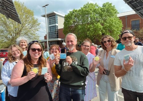 attendees hold up energy and library themed cookies: sun, solar panel, light bulb, book, and book check out card 