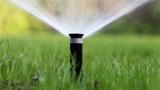 An image of a sprinkler spraying water onto grass.