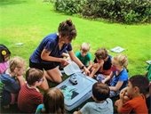 The Program Education Specialist leading a storm drain demostration for campers.