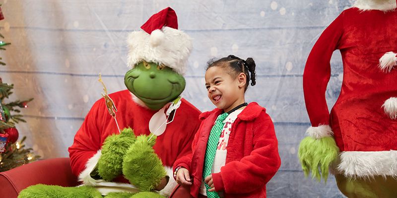 A young girl makes a face as she poses with the Grinch.
