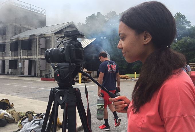 A film intern adjusts the camera at a photography shoot with firefighters