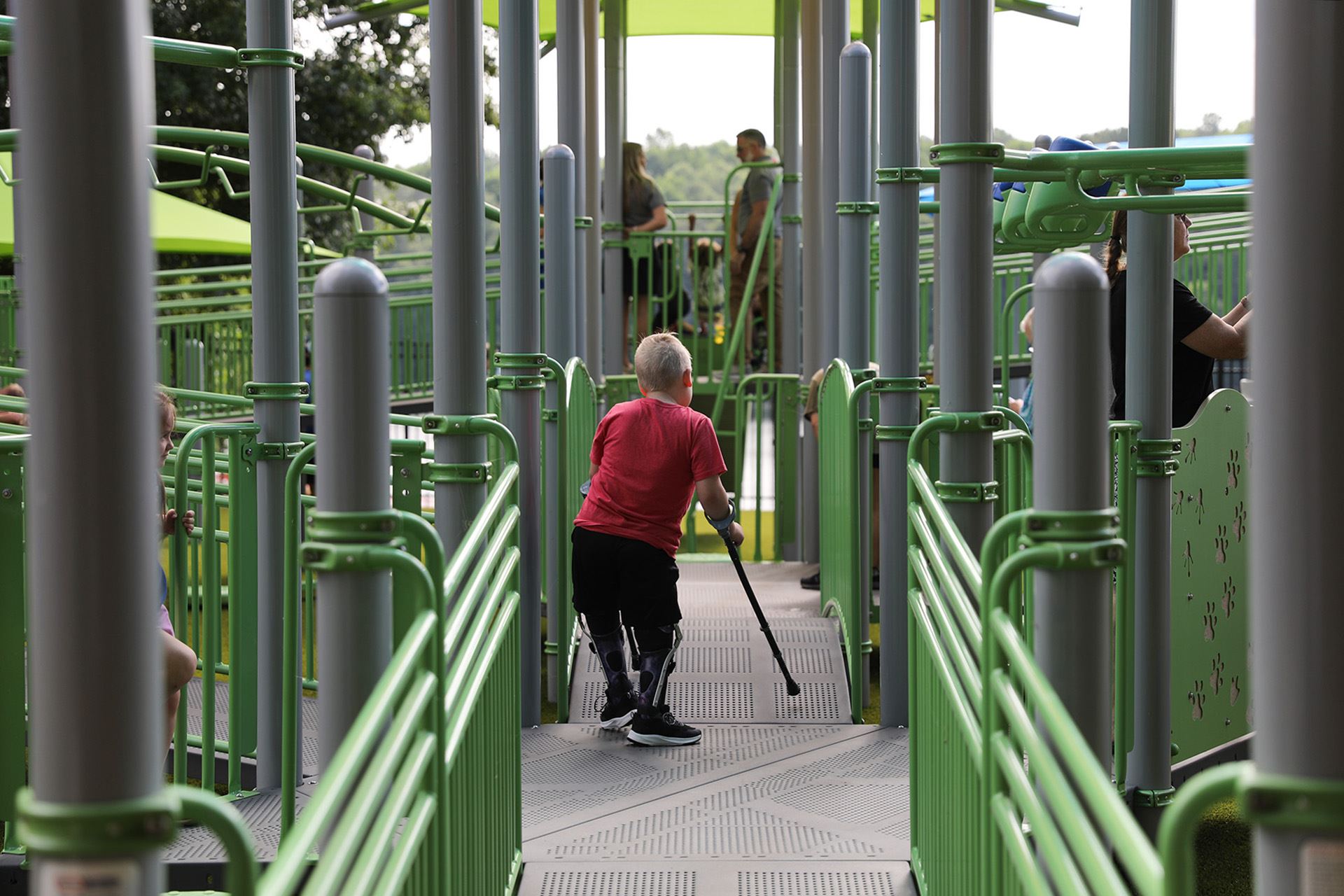 Achild with crutches enjoys the new playground at Sandy Creek Park